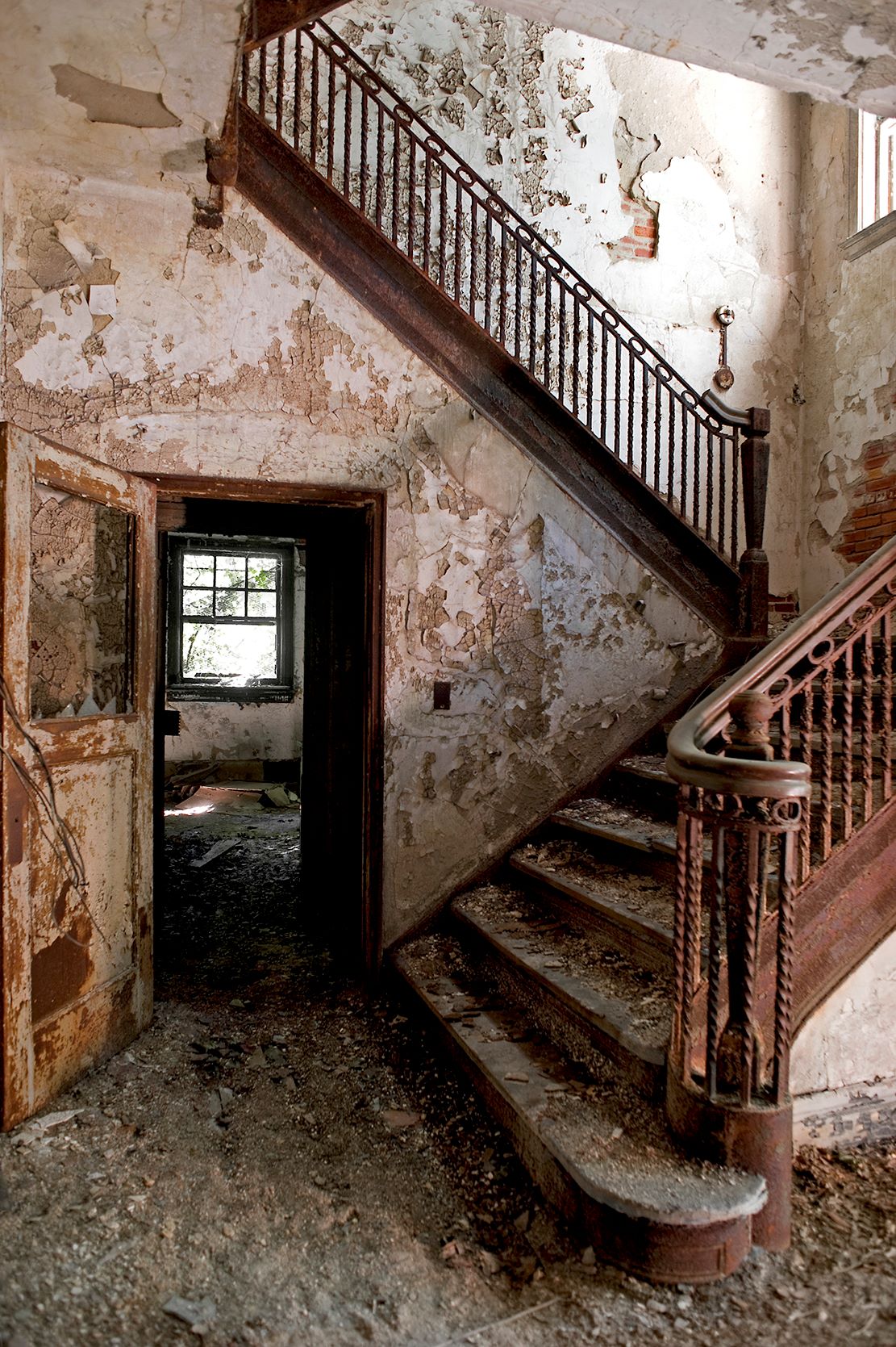 A grand staircase stands in an abandoned building